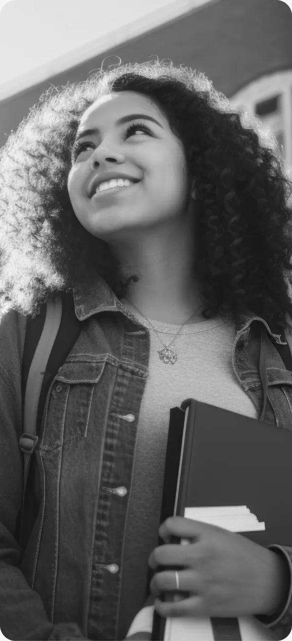 Estudante sorrindo com livros em ambiente acadêmico